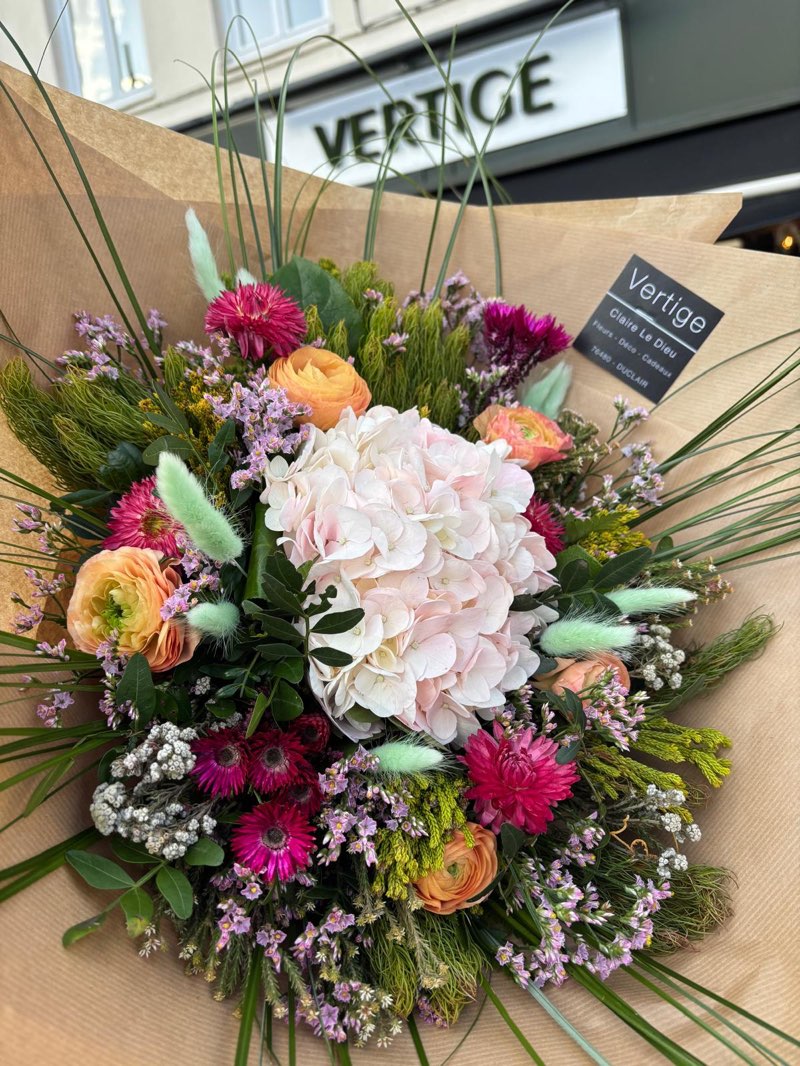 Bouquet champêtre autour d’un hortensia pâle, renoncules orange et fleurs séchées, dans le kraft Vertige