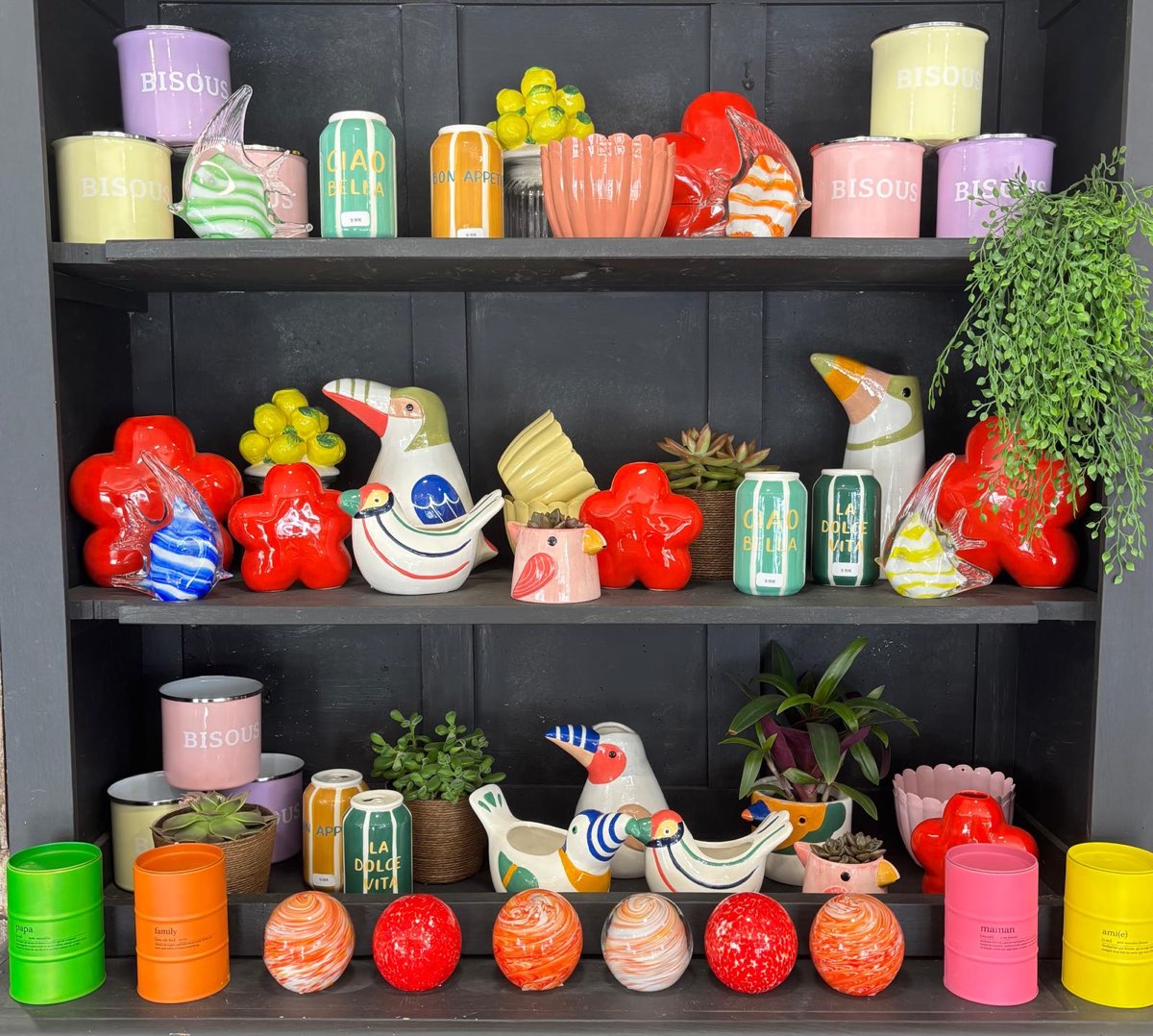 Étagères de la boutique garnies de céramiques colorées, oiseaux décoratifs et bougies