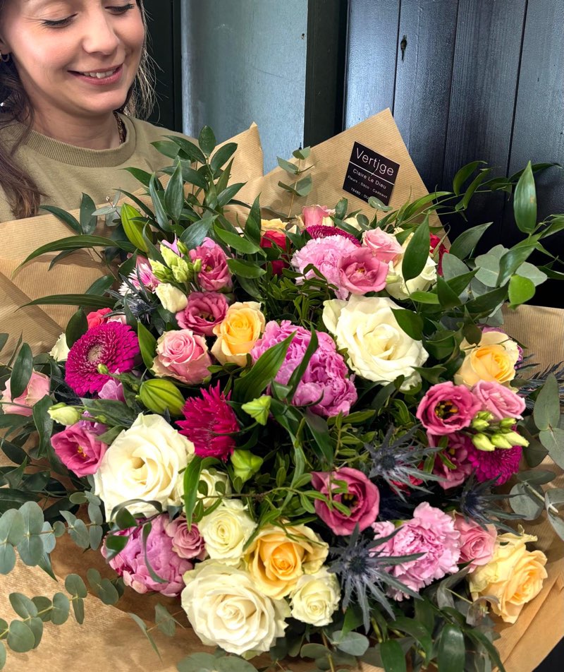 Grand bouquet généreux de roses blanches et jaunes, œillets roses, chardons bleus et eucalyptus, dans son kraft Vertige