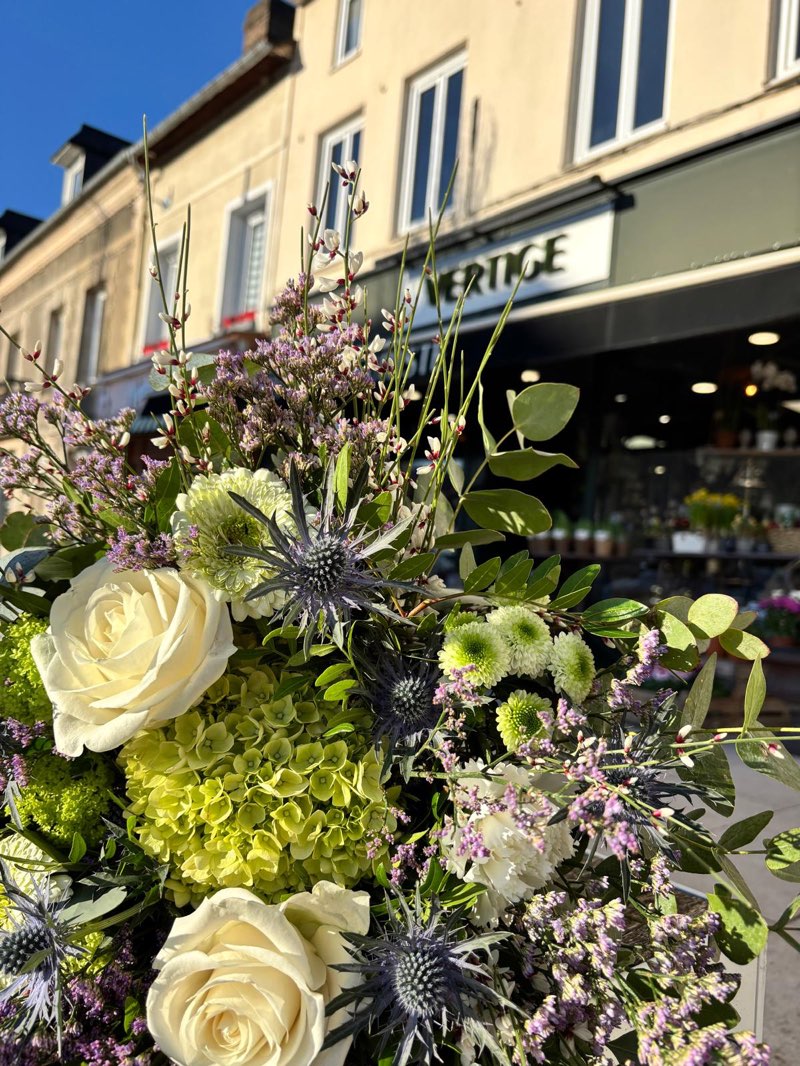 Bouquet de roses blanches, hortensia vert et chardons bleus devant la boutique