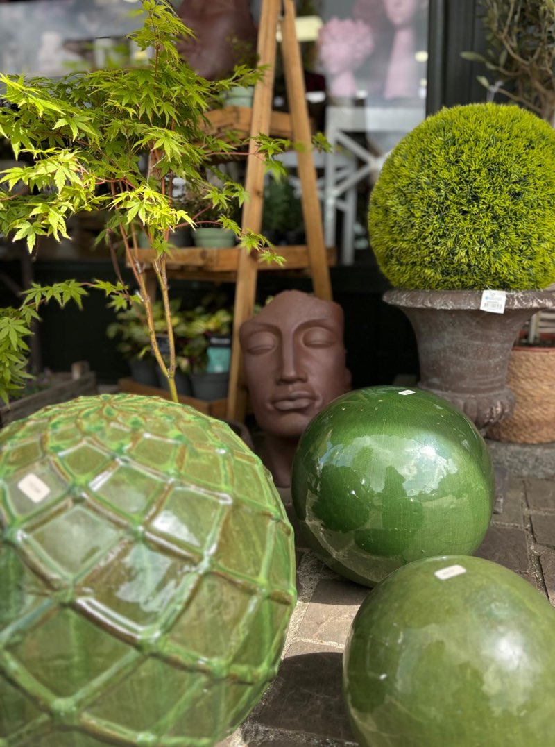 Sphères en céramique verte, érable du Japon et tête de Bouddha devant la boutique