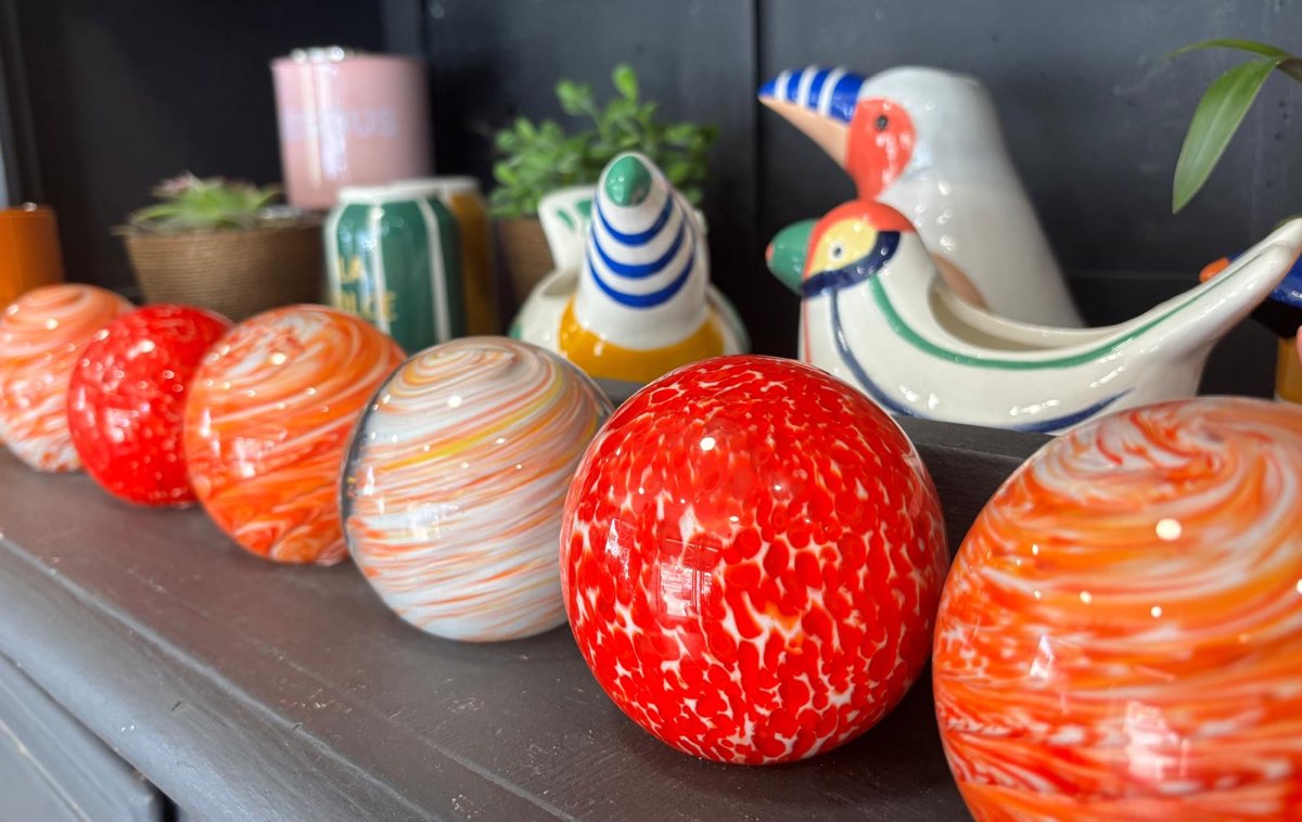 Sphères en verre soufflé tourbillonné rouge et orange alignées sur une étagère